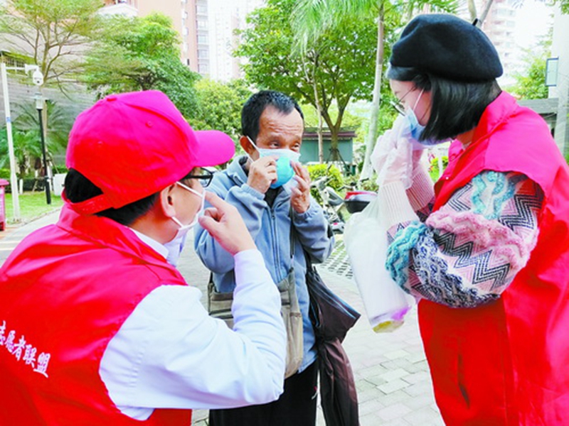 志愿者为居民示范口罩的正确戴法。（庄细香 摄）.jpg