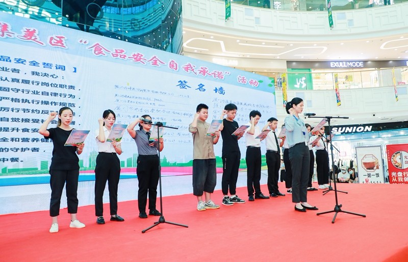 商圈食品经营单位代表在“食品安全自我承诺”承诺墙上签名并公开宣誓，进一步提升食品行业诚信自律水平（区市场监管局供图）.jpg