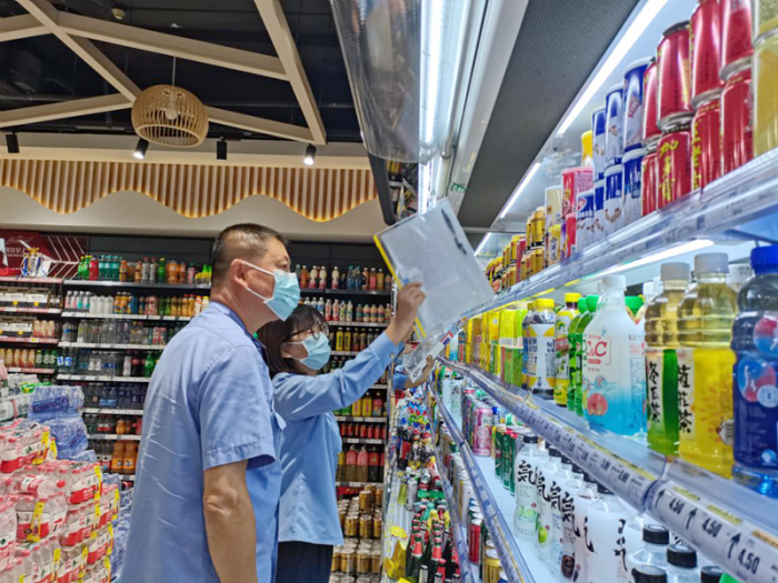 区市场监管局相关工作人员检查便利店保健食品(饮料)(区市场监管局供图).png